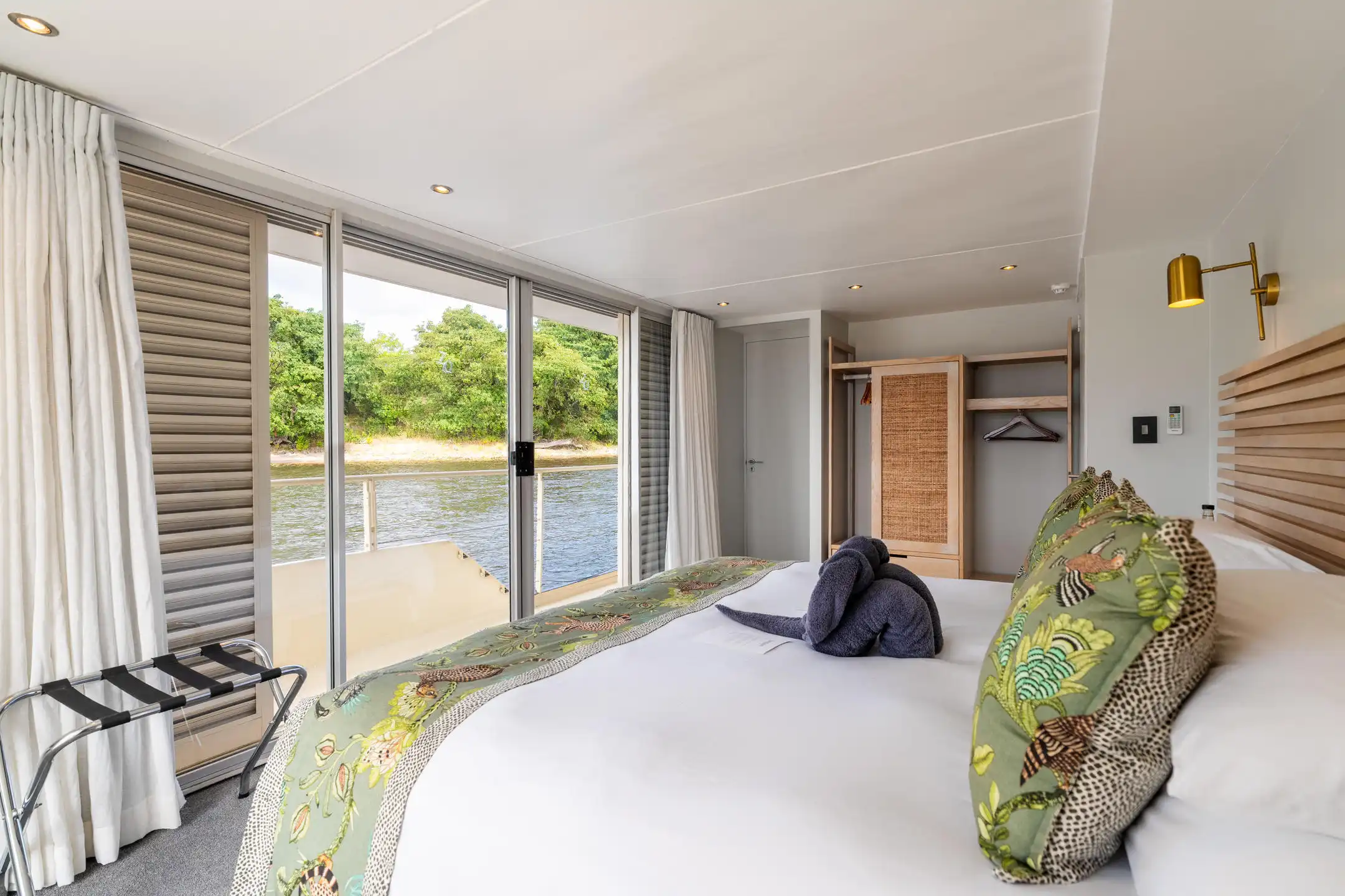 Luxury safari suite on river cruise with towel animal. African photo safari lodging with balcony view.