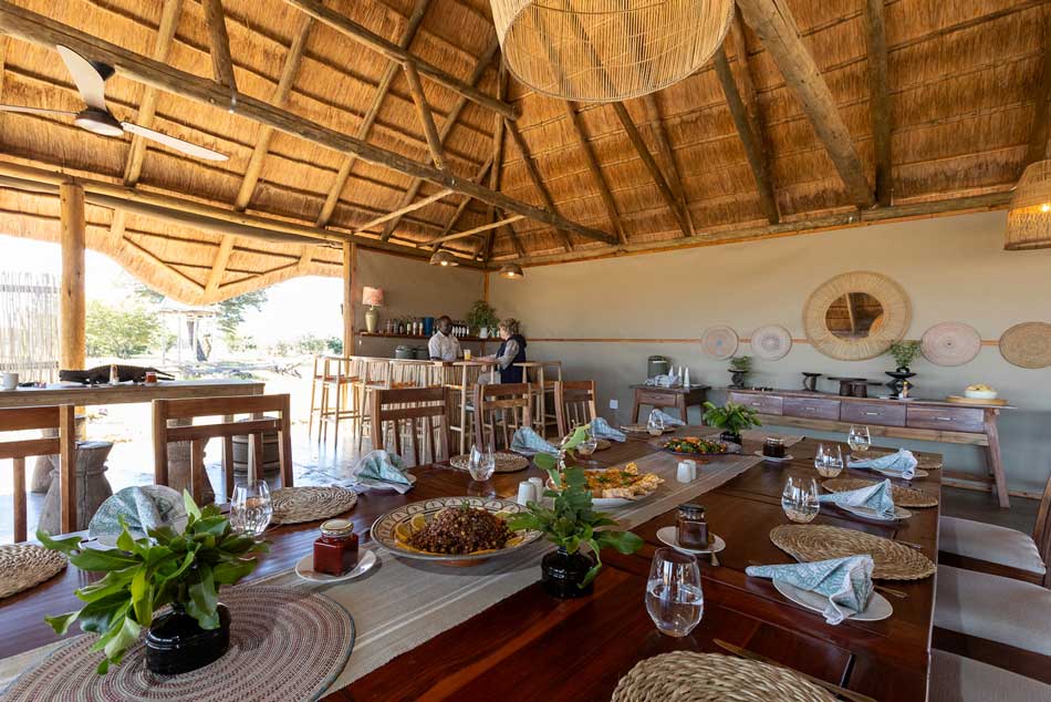 Camp Hwange dining area with thatched roof, set table, and bar for an African safari photo safari experience.