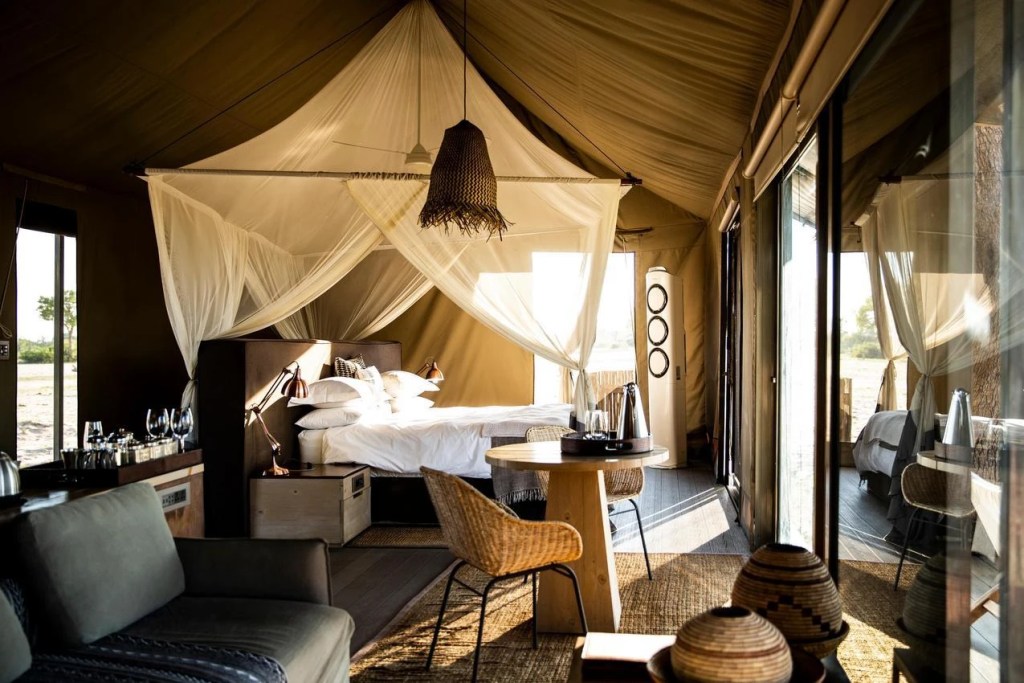 Luxury safari tent interior with draped bed, seating area, and natural light. African safari photo safari