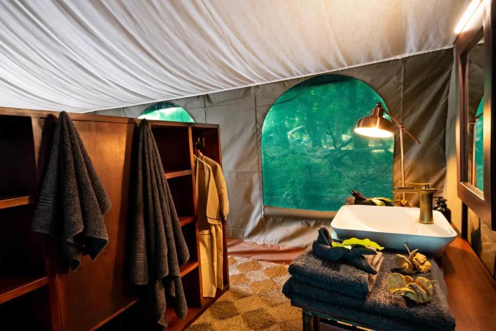 Luxury safari tent bathroom with forest view. African photo safari accommodation.