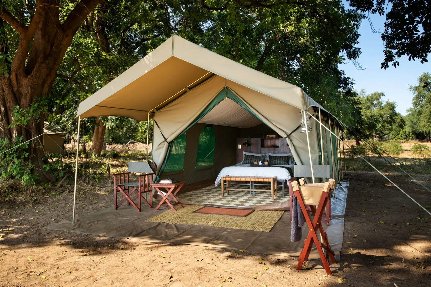 Luxury safari tent with bed and chairs, offering a comfortable photo safari experience in the African safari.