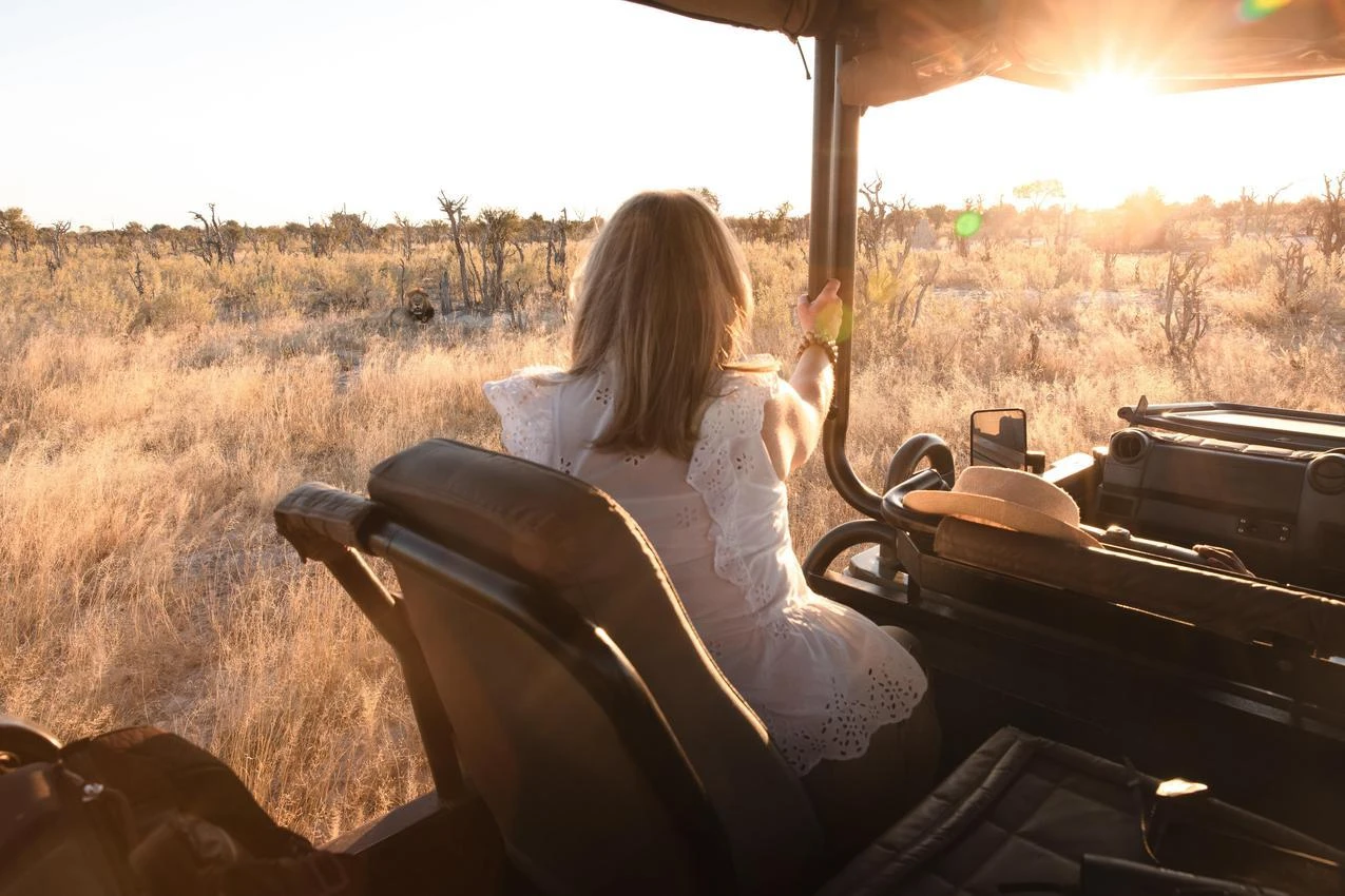 Woman on African photo safari, enjoying the golden light over the savanna.