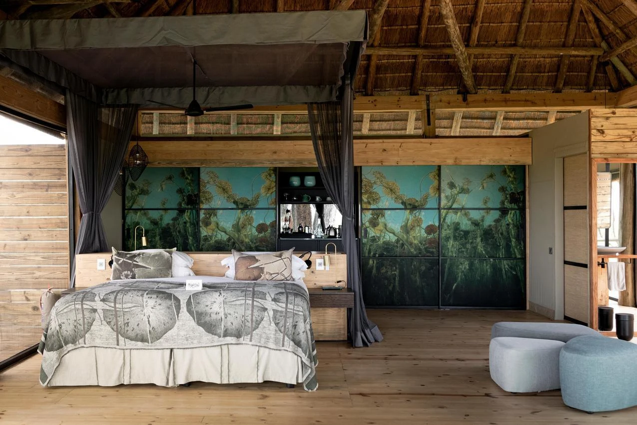 African safari lodge bedroom with four-poster bed, thatched roof, and nature-themed decor. Photo safari accommodation.