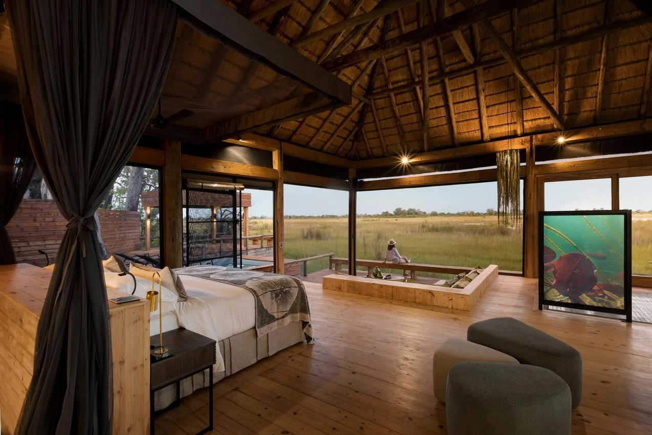 Luxury African safari lodge interior with thatched roof, wooden floors, and view of the savanna. Photo safari experience.