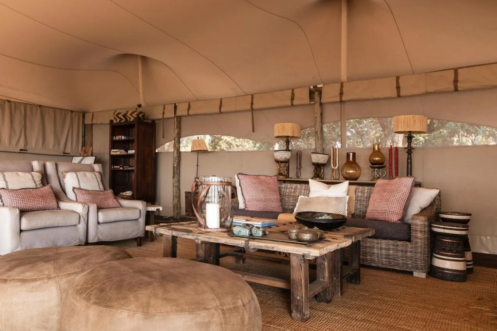 Luxury safari tent interior with rustic wood furniture and comfortable seating. African safari photo opportunity.