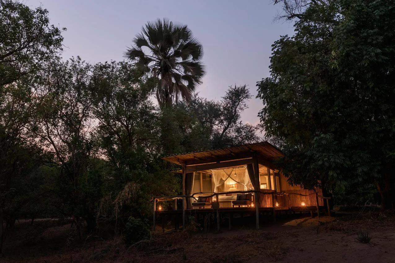 Luxury safari tent at dusk, lit by lanterns on an African photo safari.