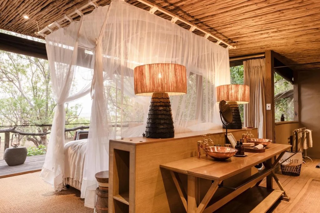 Safari lodge bedroom with canopy bed, copper sinks, and rustic decor. African safari photo safari.