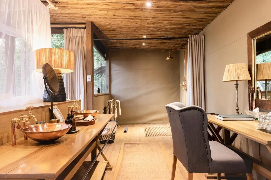 Luxury safari bathroom with copper sinks, wood accents, and an open shower area. African safari photo.