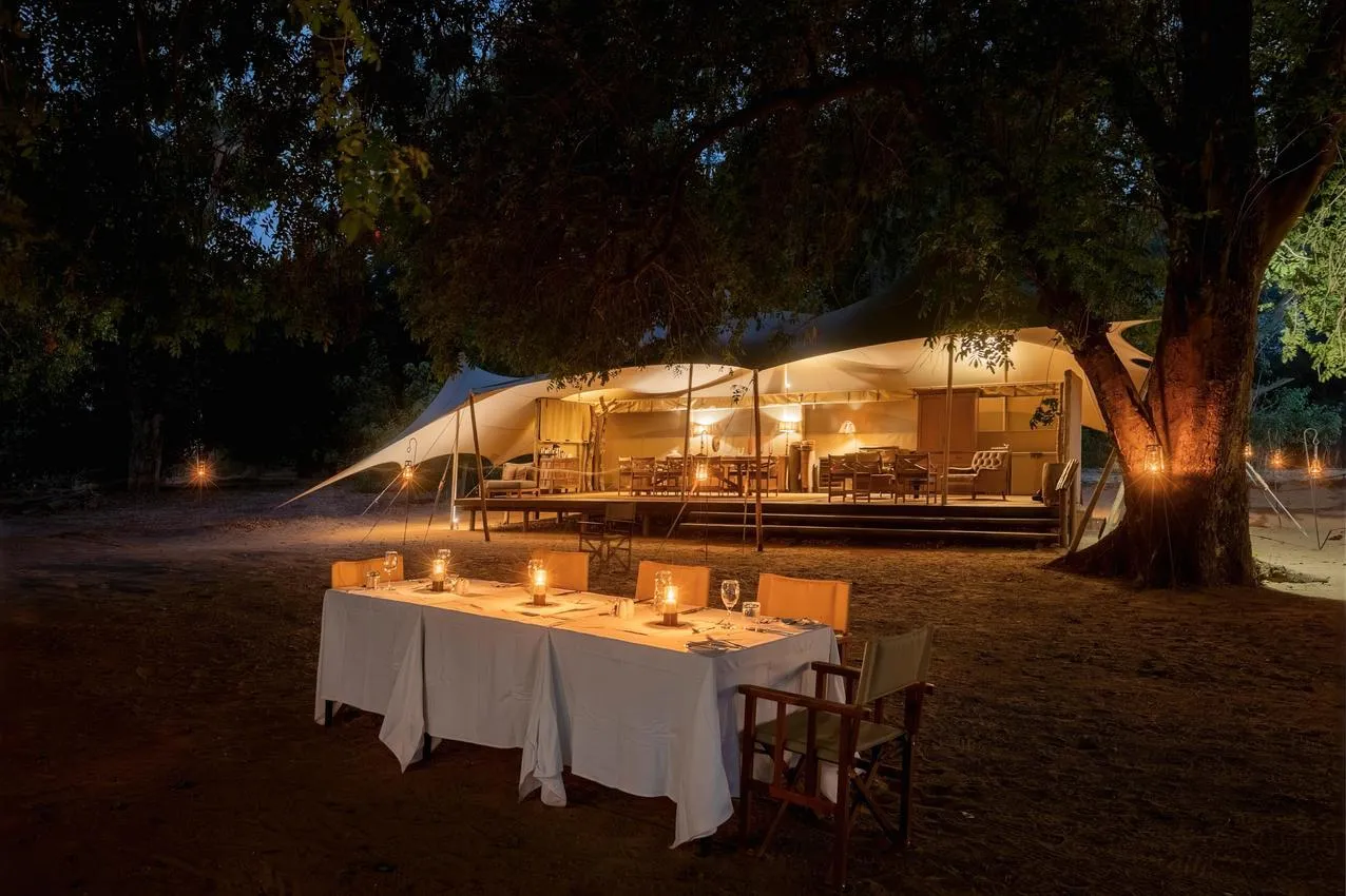 Outdoor dining at an African safari lodge, lit by candlelight. Photo safari experience.