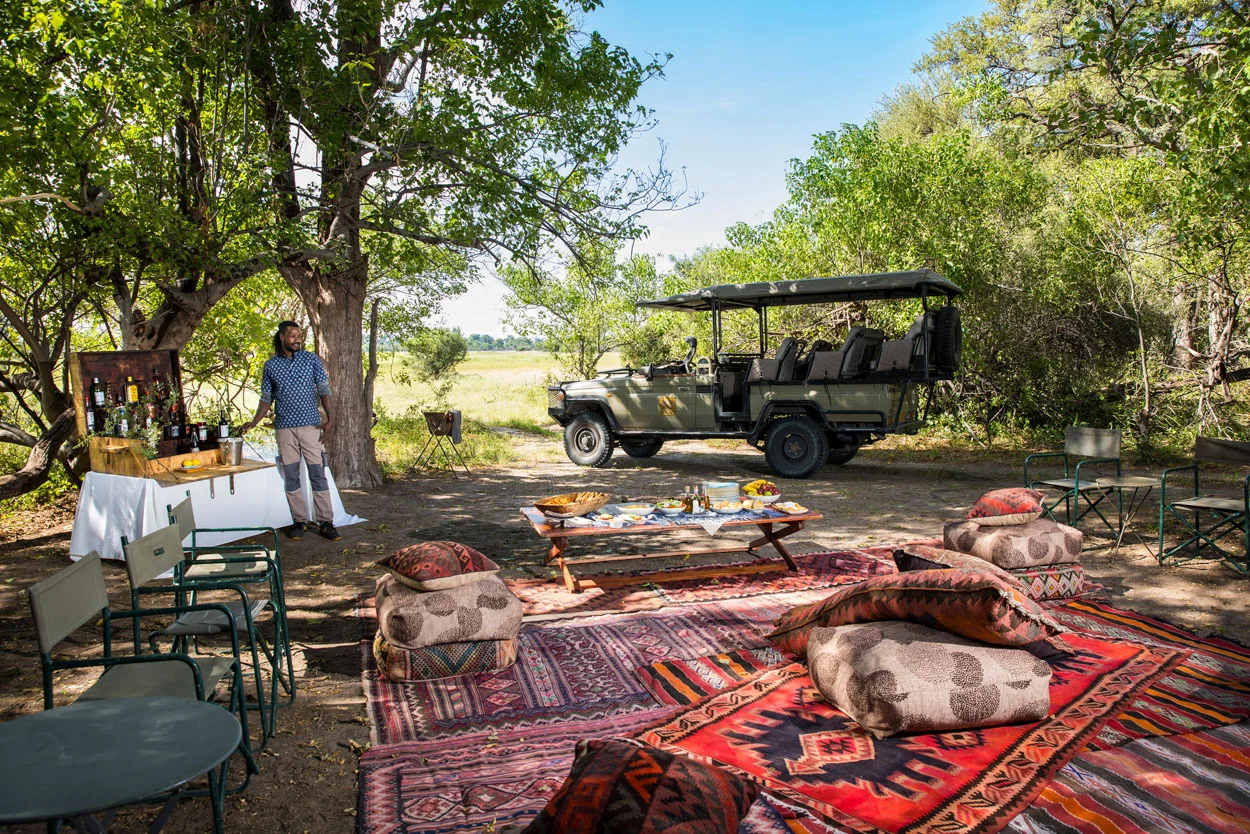 African photo safari: Safari vehicle and outdoor dining setup in Botswana. Luxury African safari experience.