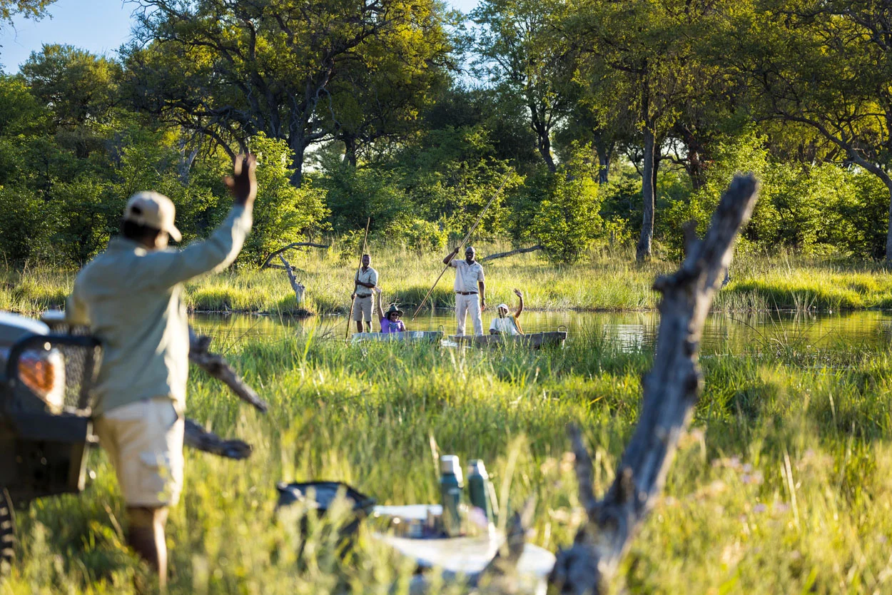 African safari: People in mokoro canoes on a photo safari, waving to guide.