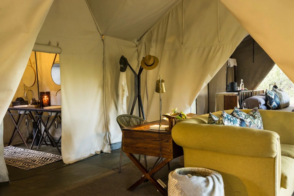 Luxury safari tent interior with sofa, desk, and bathroom. African safari and photo safari style.
