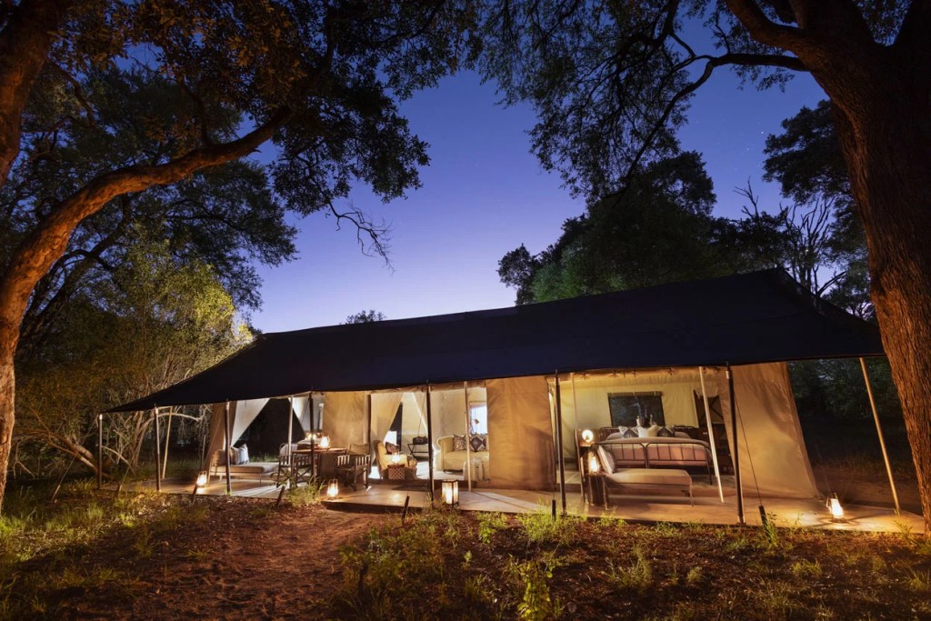 Luxury safari tent lit at dusk, offering a premium African photo safari experience.