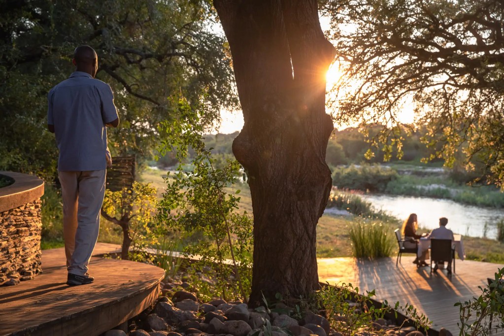 Man on safari deck overlooking river at sunset, Uganda expedition photo safari
