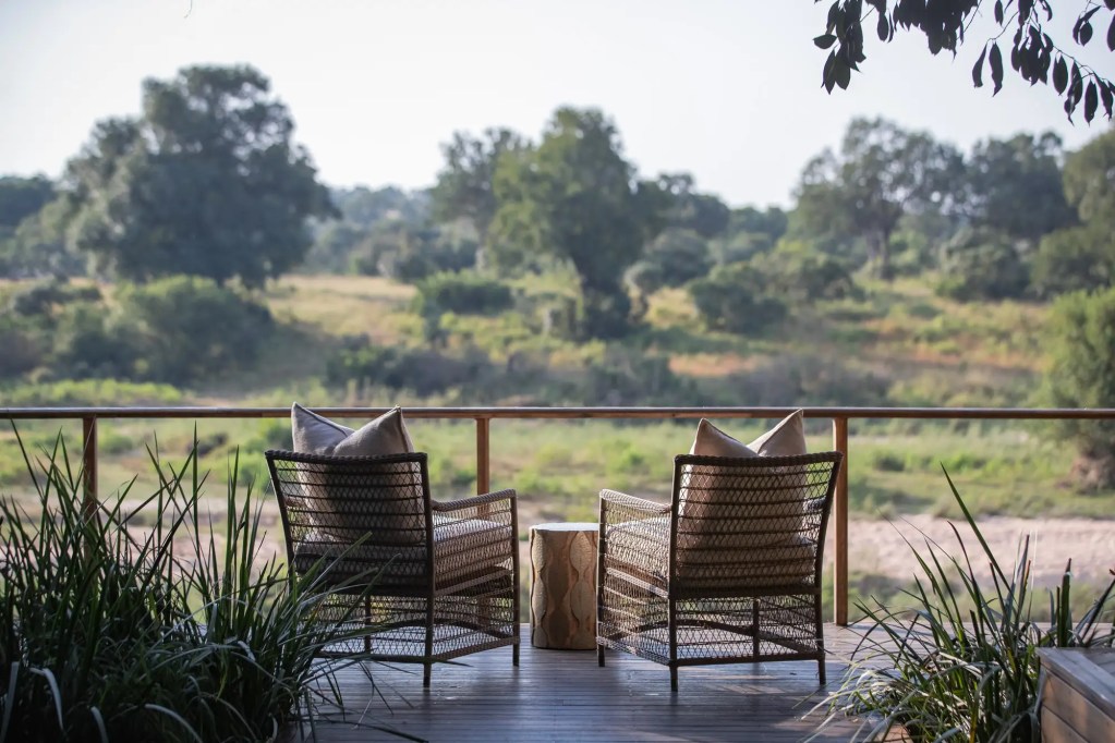 African safari lodge deck with chairs overlooking savanna landscape, Uganda photo safari