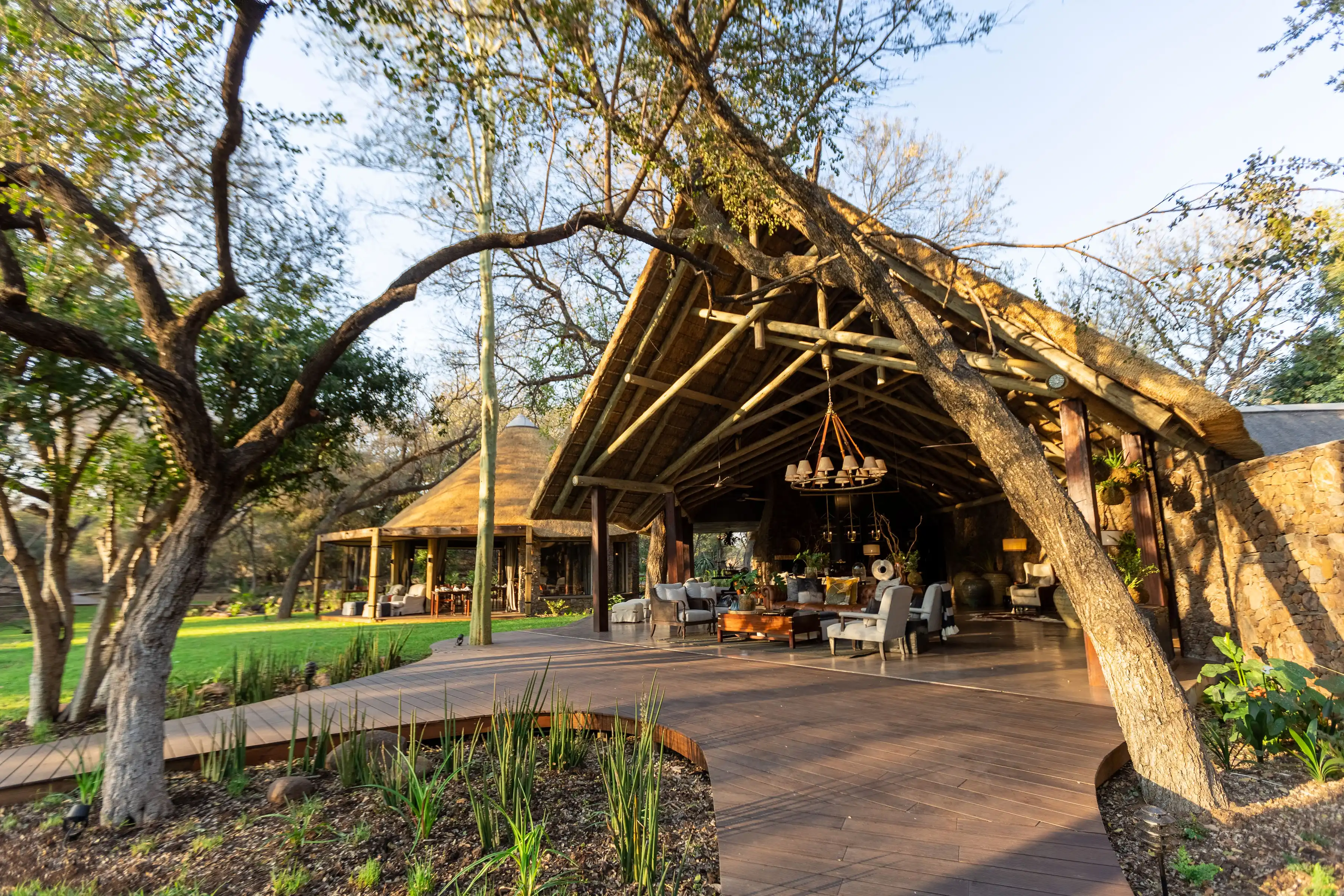 African safari lodge lounge area with thatched roof, wooden deck, and lush greenery during a photo safari.