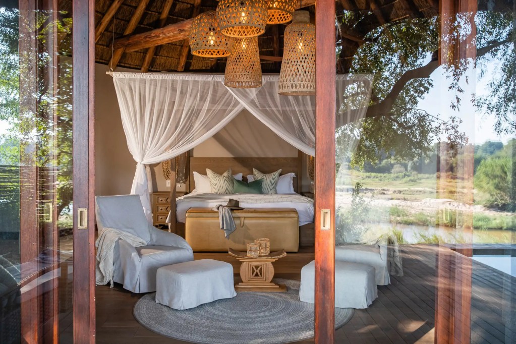 Luxury safari tent bedroom with canopy bed and river view, Uganda photo safari.