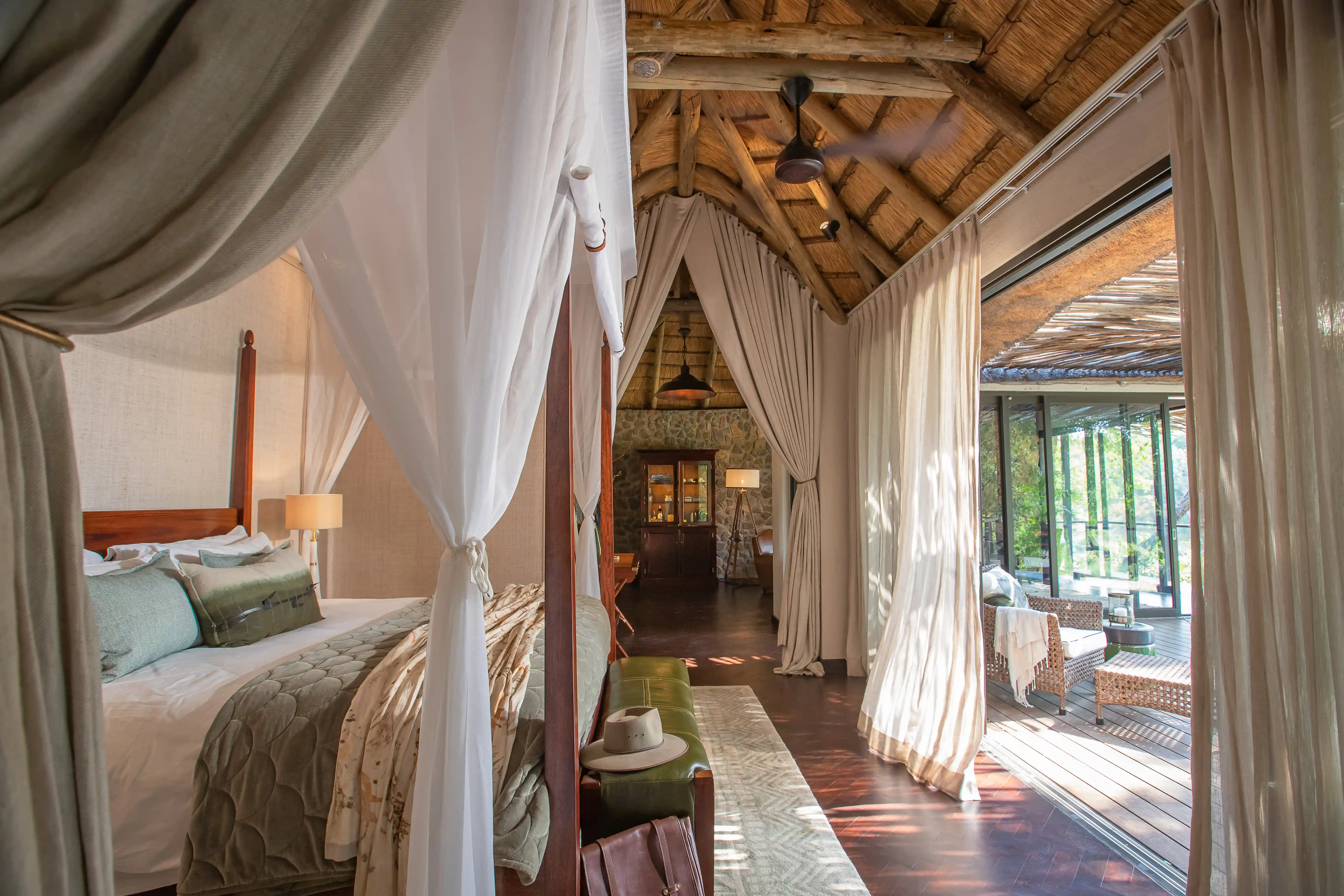 Luxury Sabi Sand safari lodge bedroom with thatched roof and open-air deck.