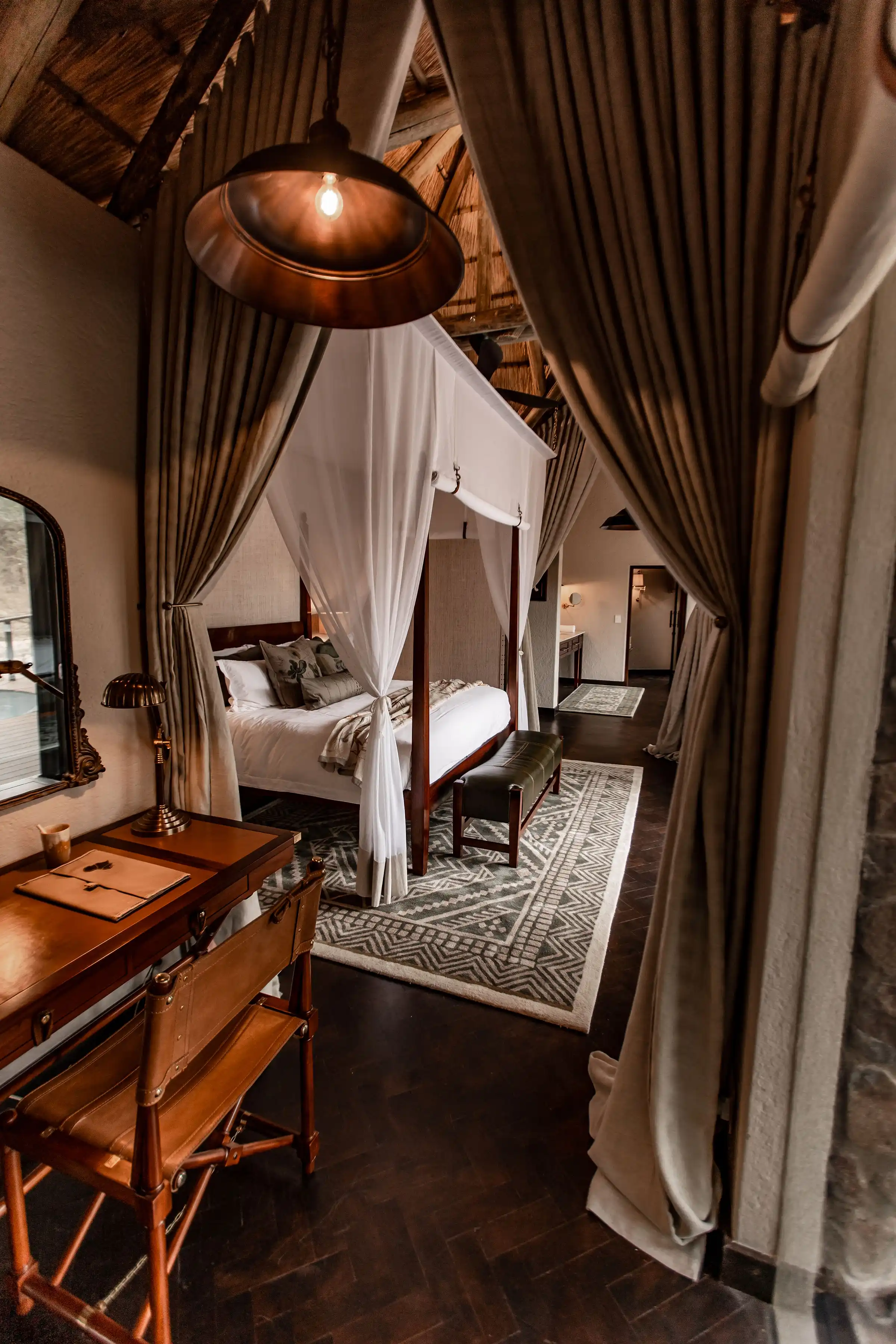 Luxurious Sabi Sand safari lodge bedroom with canopy bed, desk, and African safari decor.