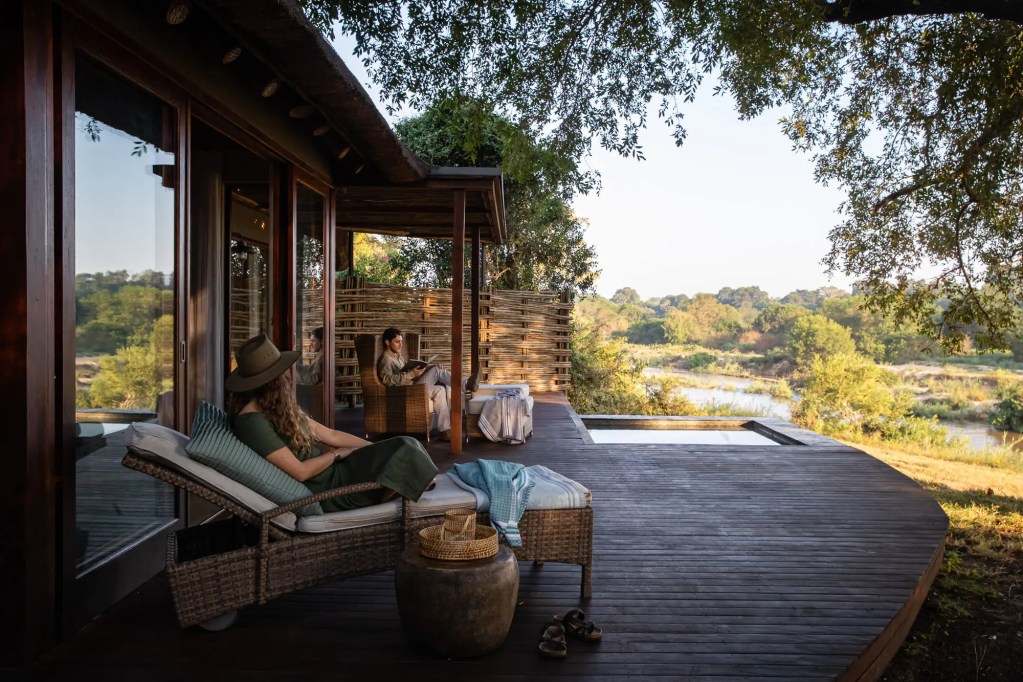 African safari lodge deck with guests relaxing, overlooking savanna landscape. Photo safari.