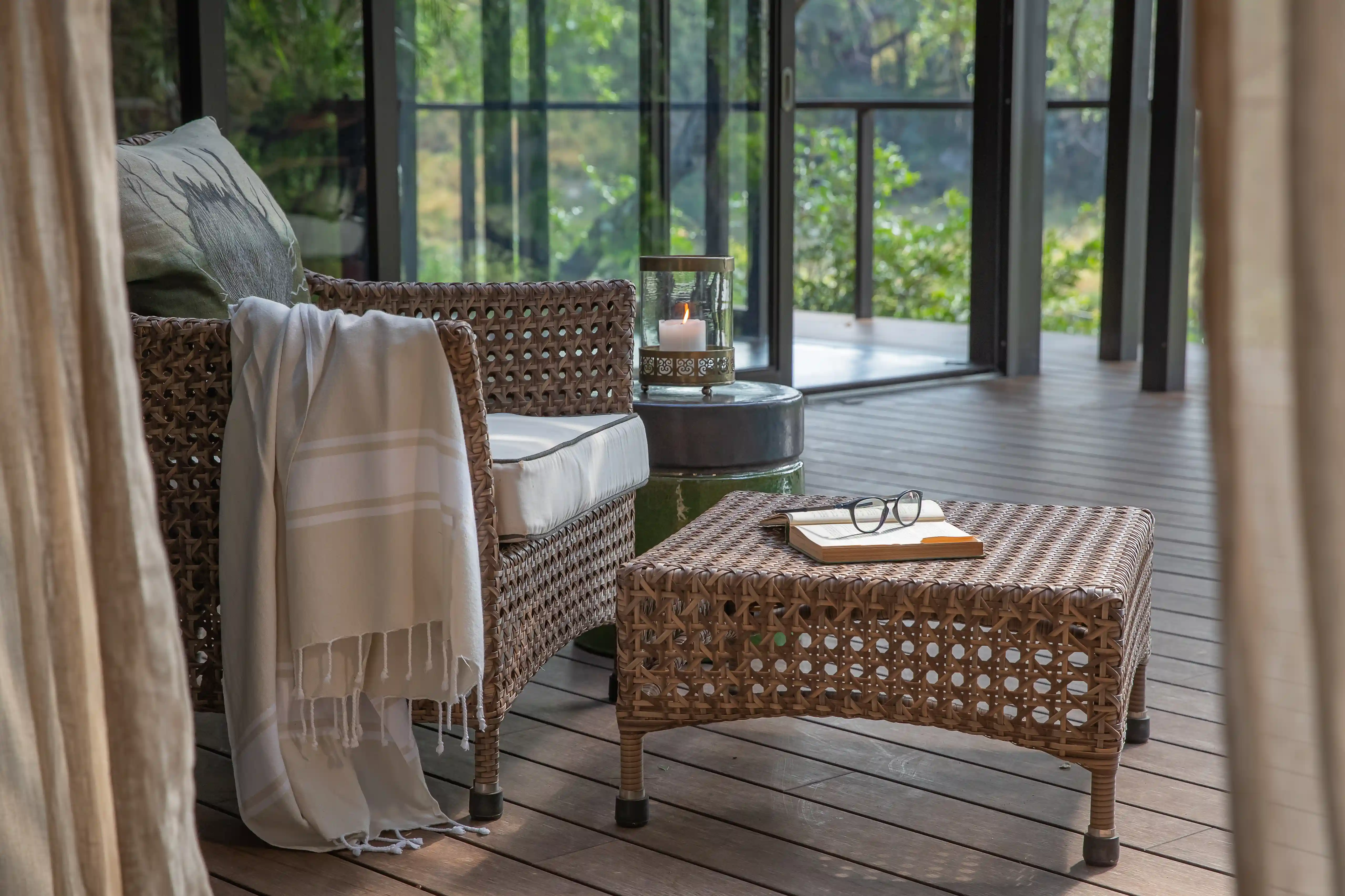 African safari photo: Wicker chair, table with book & glasses on lodge deck.