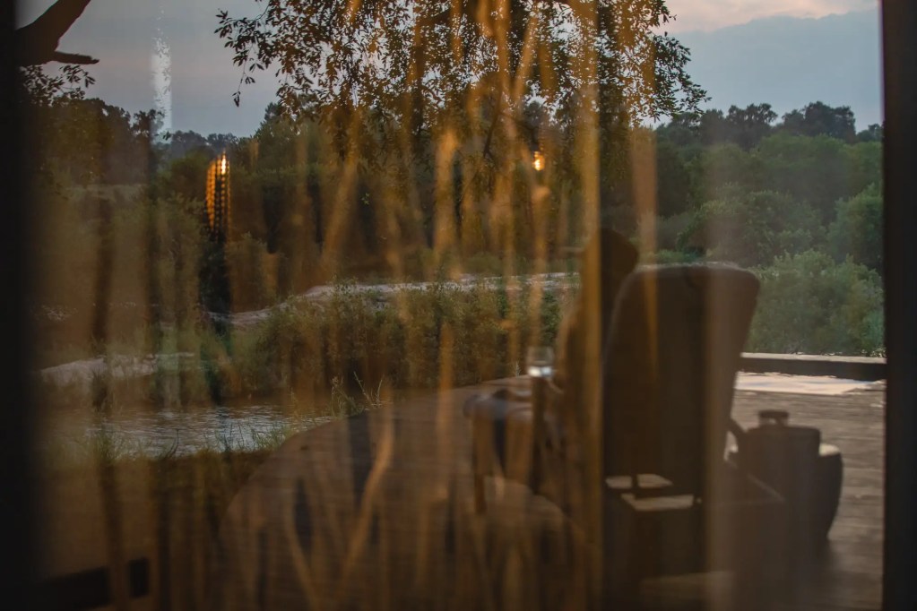 African safari lodge deck at dusk, with view of river and trees on Uganda expedition photo safari.