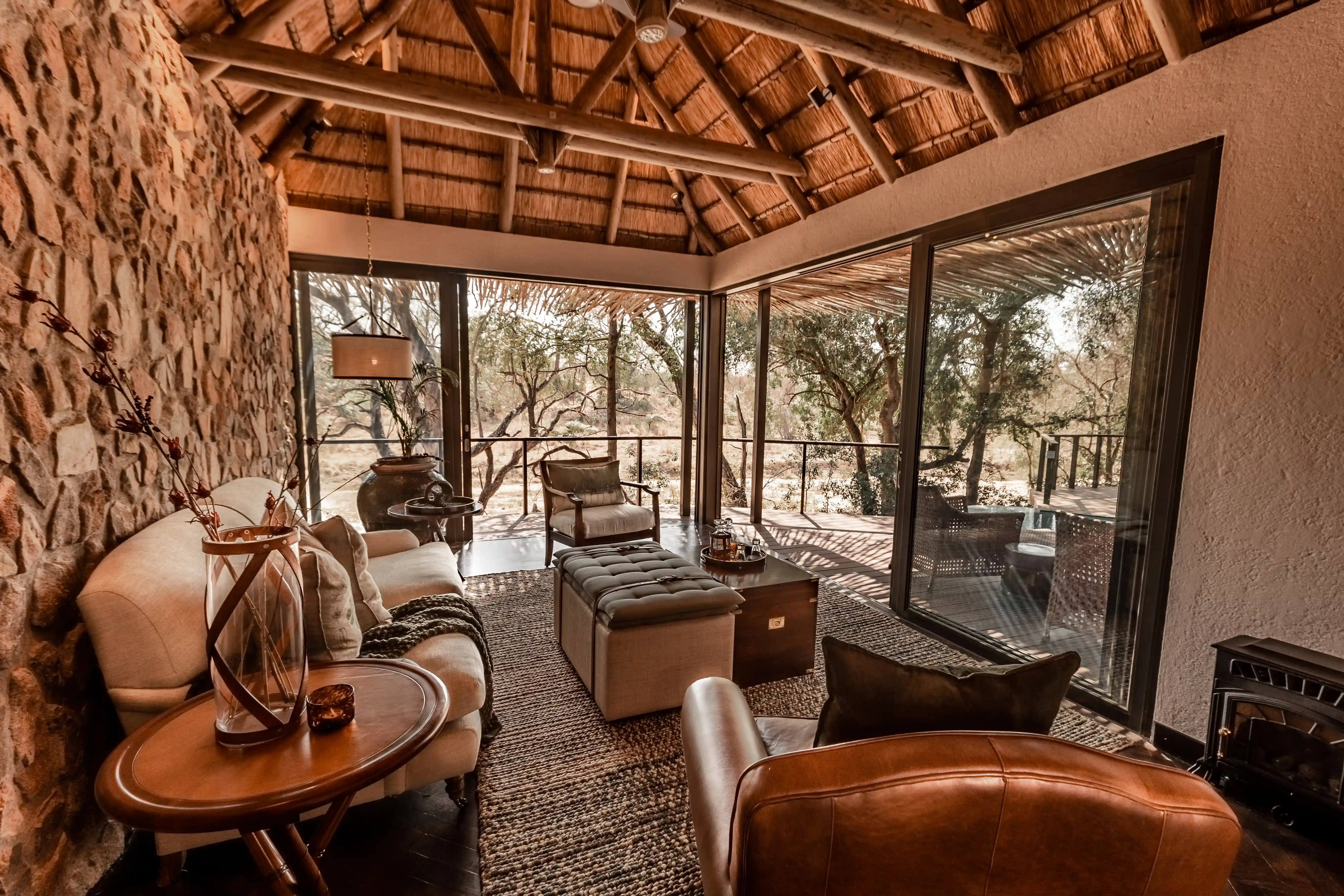 Luxury Sabi Sand safari lodge lounge with stone walls, thatched roof, and bush views.