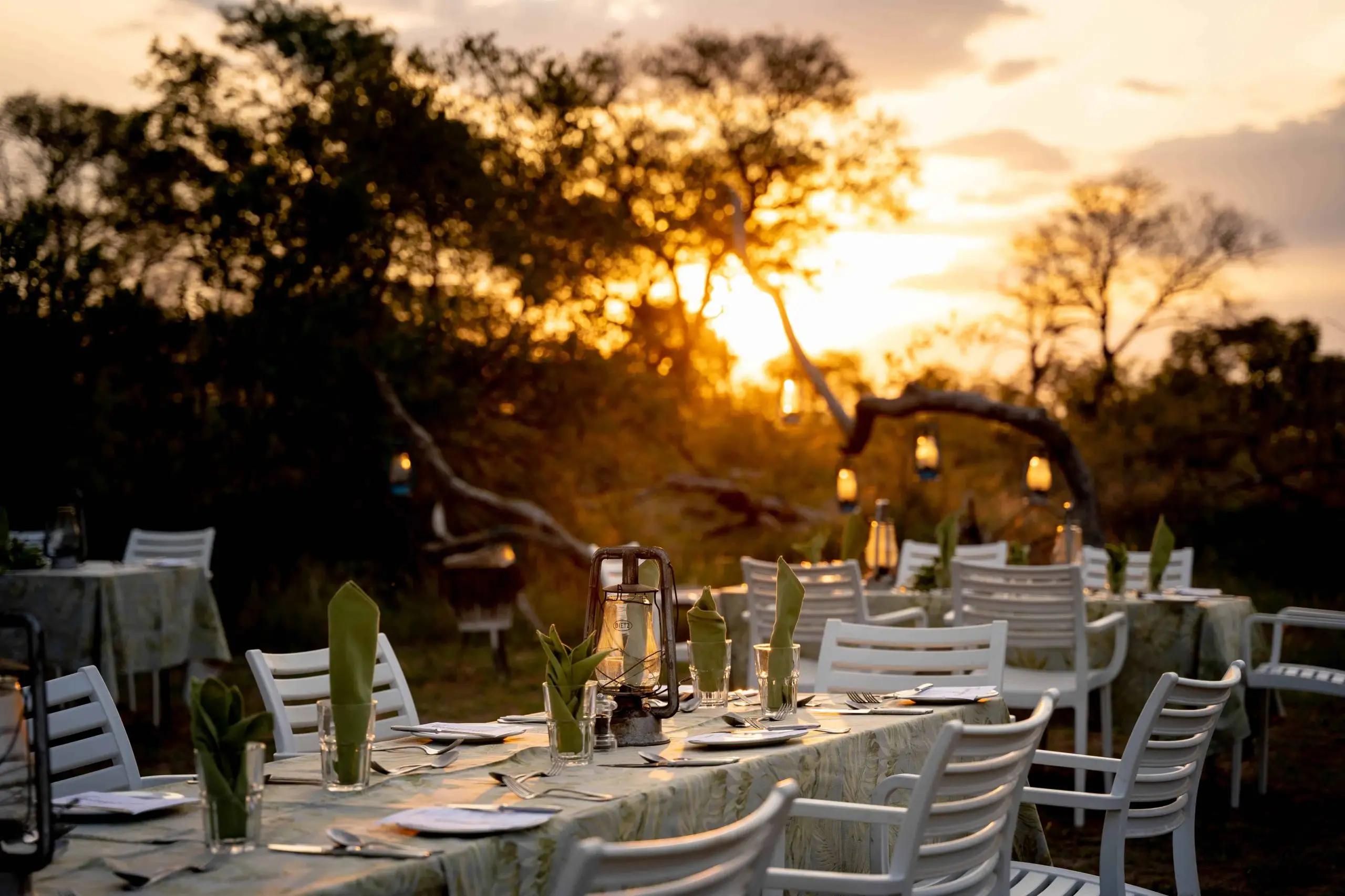 African safari dining setup at sunset, with lanterns and tables set for a photo safari evening.
