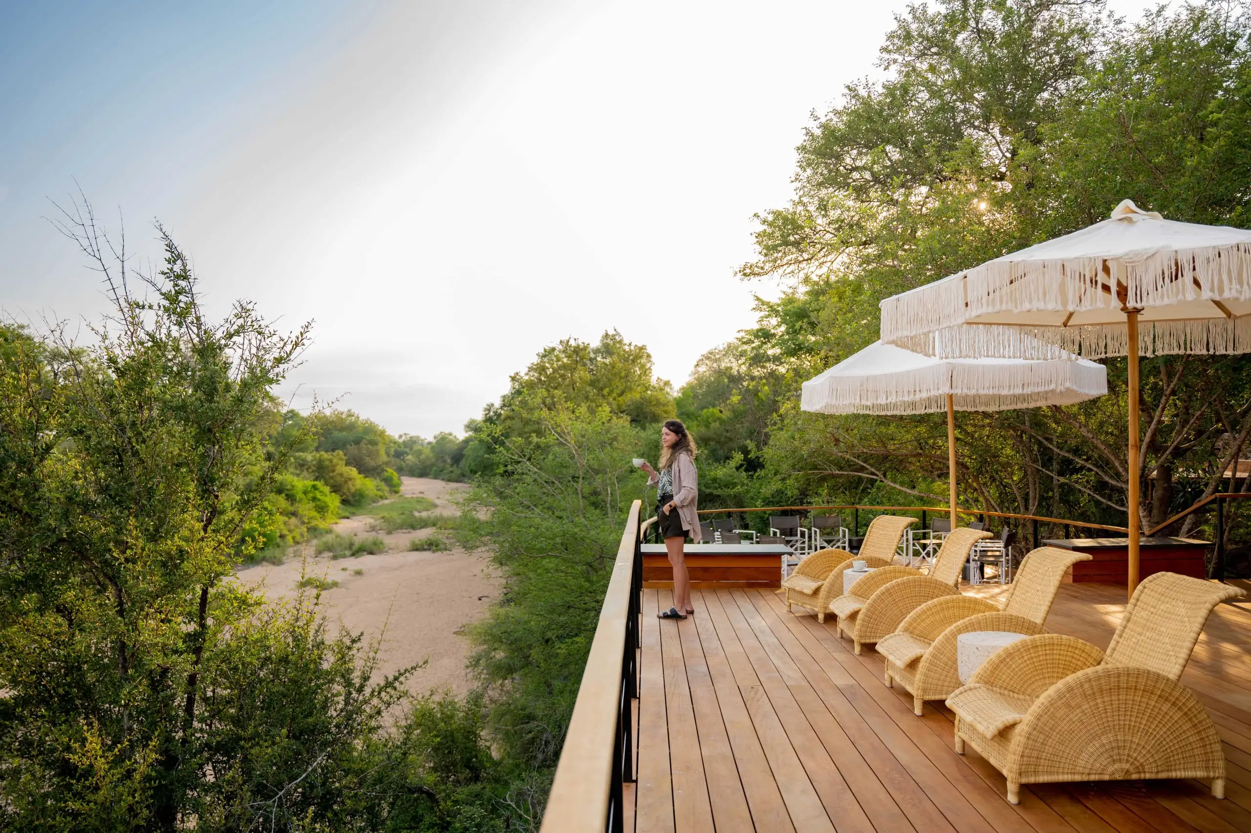 Woman on deck overlooking African safari landscape; Timbavuti Legacy photo safari.