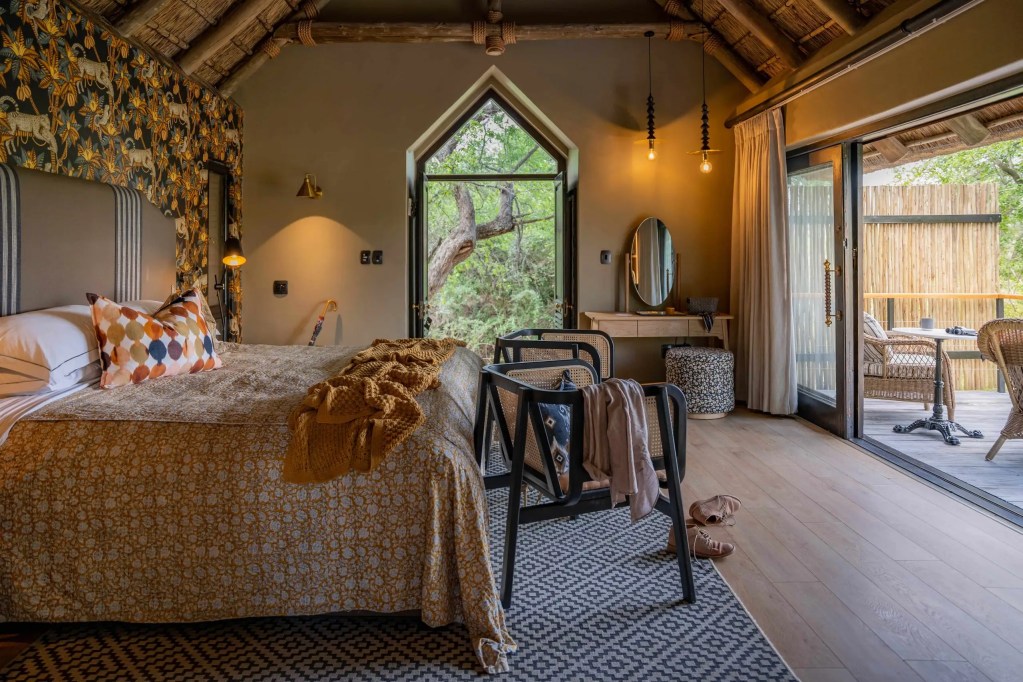 Luxury safari lodge bedroom with African wildlife wallpaper, open to nature