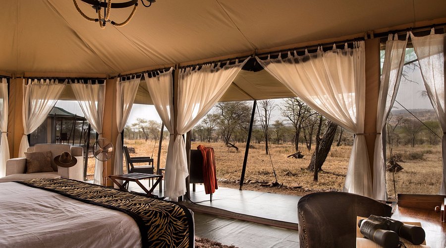 Luxury tent interior with a bed and view of the Serengeti plains for an African safari photo tour.