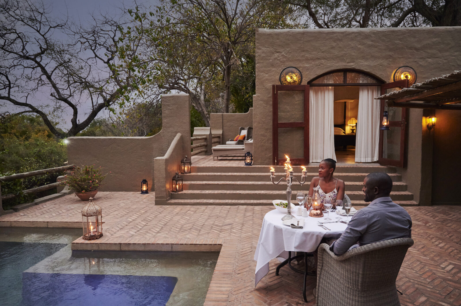Couple dining by pool at luxury African safari lodge during Chobe Signature 7nt tour.