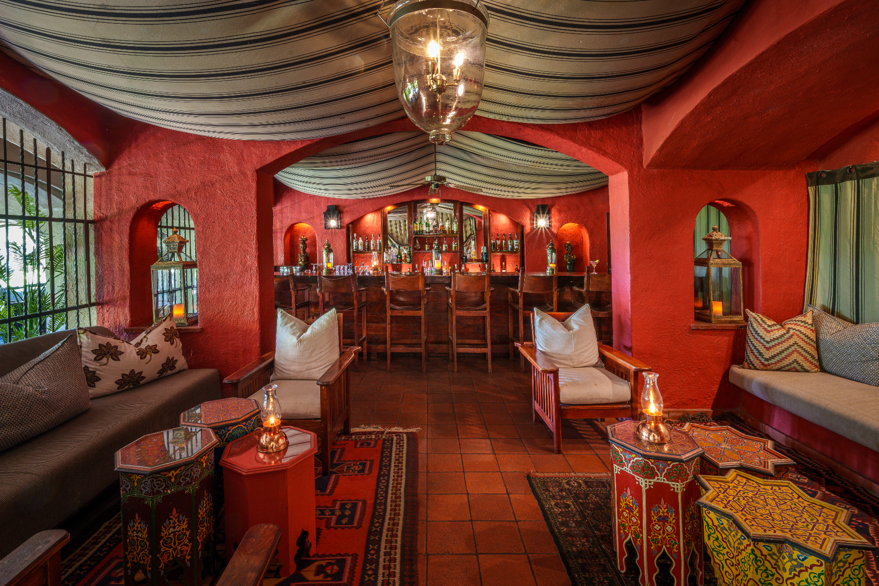 Chobe Signature 7nt: African safari photo safari lounge with red walls, bar, and seating.