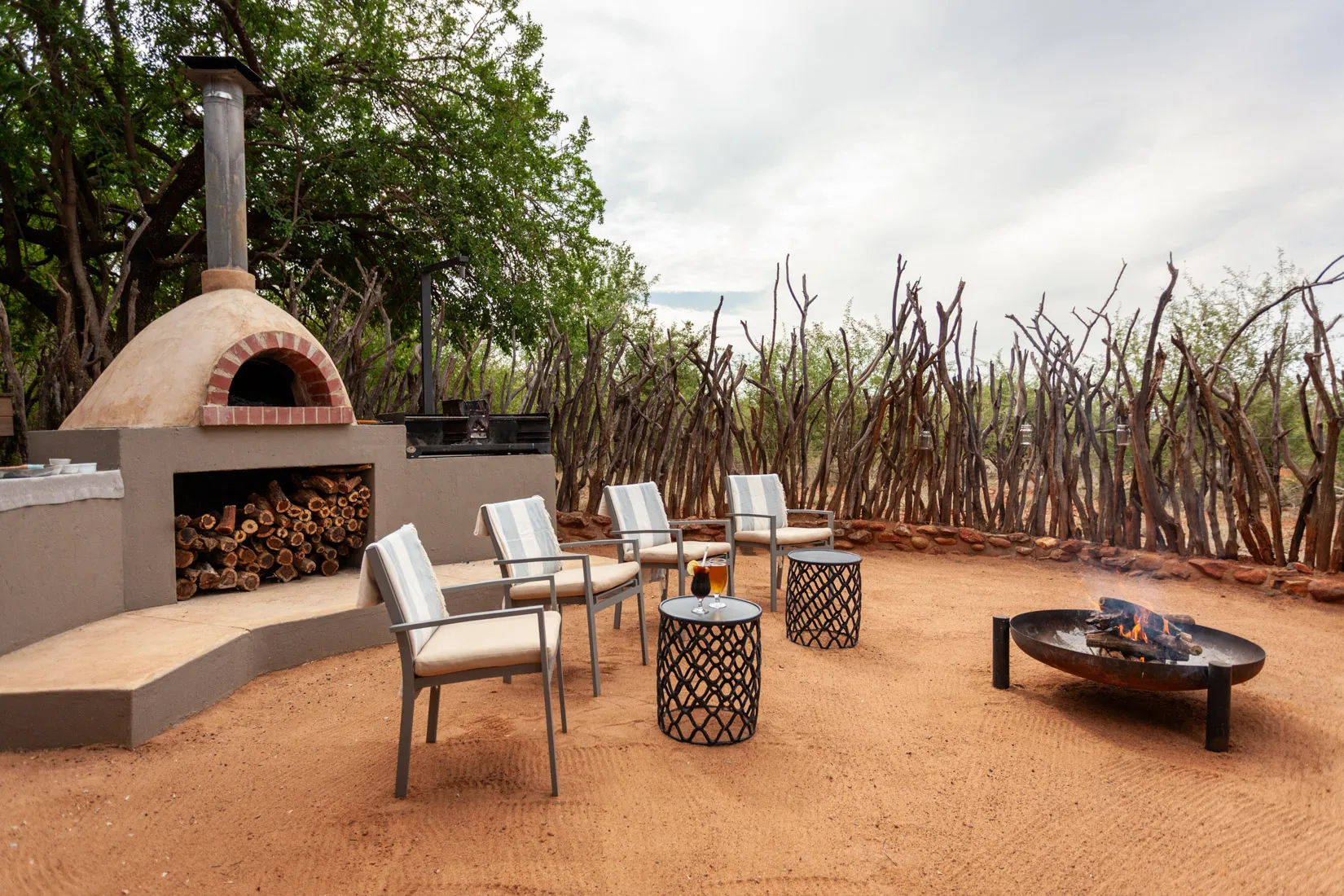 Outdoor patio with pizza oven, fire pit, and seating, perfect for a photo safari in Africa.