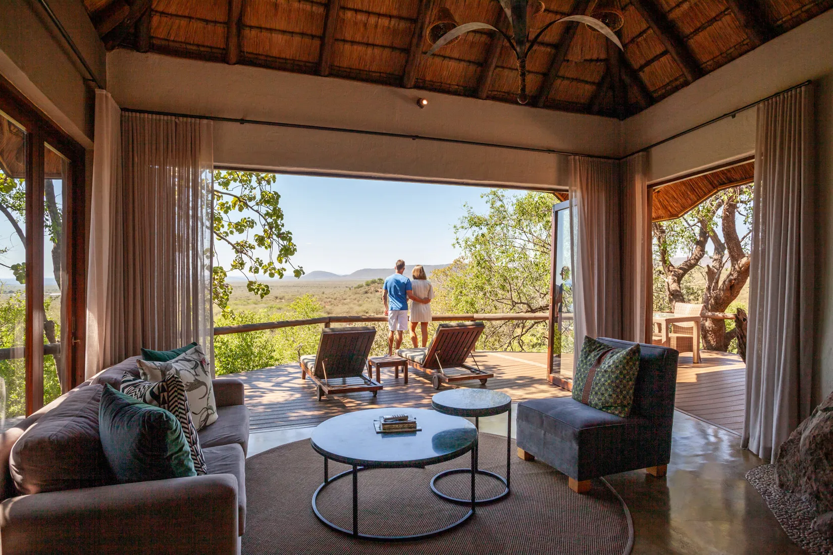 Couple on deck of luxury safari lodge, Madikwe, South Africa, enjoying African landscape photo safari